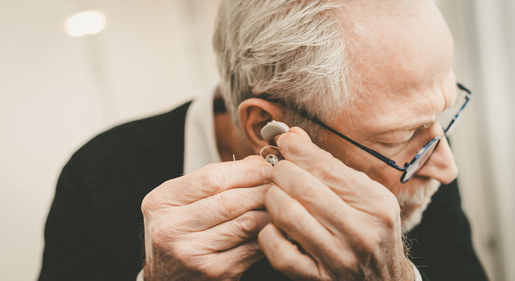 man adjusting hearing aid